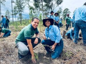 Volunteers kneeling beside a newly planted seedling
